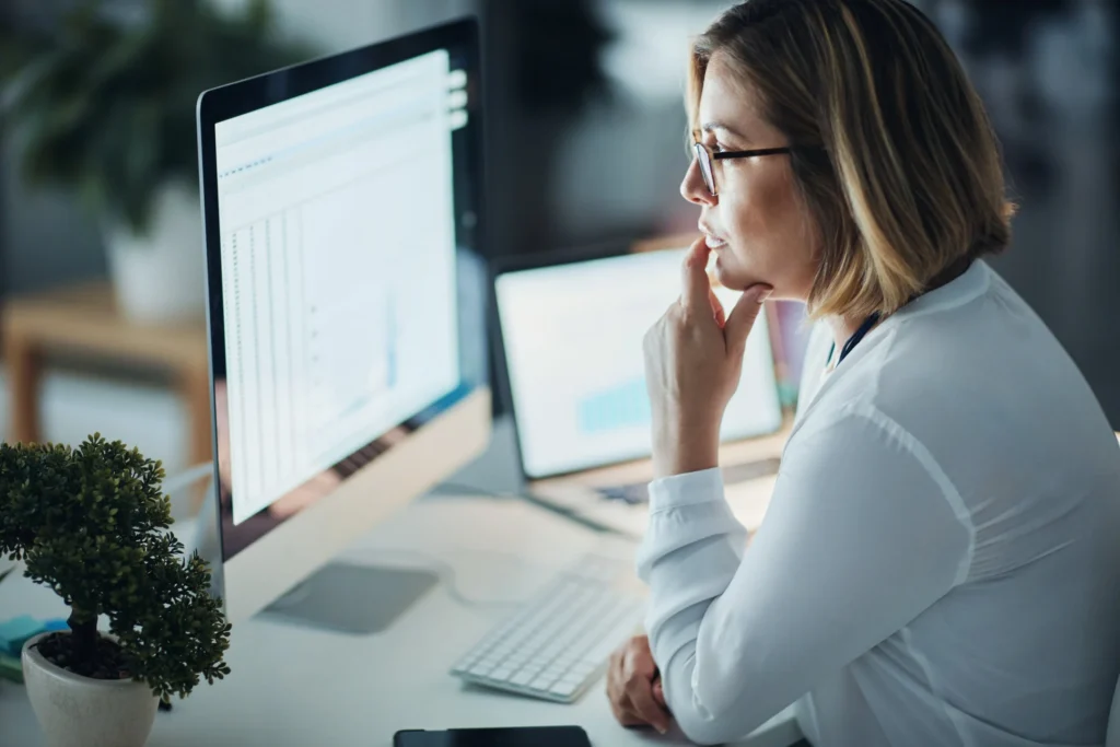 Professional translator reviewing certified document on computer monitor at modern office desk.